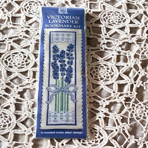 May include: A Victorian Lavender Bookmark Kit in a blue package. The bookmark design features a cross-stitch pattern of lavender flowers tied with a blue ribbon. The package includes the text "Victorian Lavender Bookmark Kit" and "a counted cross stitch design".