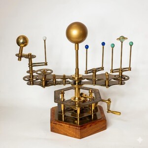 May include: A brass and wood model of a solar system, featuring a large golden sphere representing the sun, with smaller spheres and gears representing planets. The model is mounted on a wooden base.