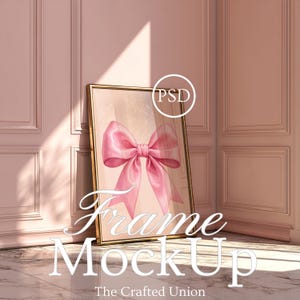 May include: A framed art print mockup featuring a watercolor pink bow on a light background. The gold frame leans against a pink wall. The text "Frame Mockup" and "The Crafted Union" are visible.