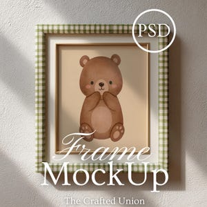 Può includere: Un'opera d'arte incorniciata con un'illustrazione ad acquerello di un orsacchiotto marrone. La cornice ha un bordo interno bianco e un bordo esterno a quadretti verdi e bianchi. Le parole "Frame MockUp" sono visualizzate in corsivo.