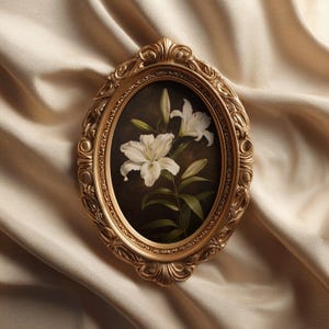 Pu&ograve; includere: Una cornice ovale dorata e ornata con un dipinto di gigli bianchi. I gigli hanno steli e foglie verdi su uno sfondo marrone scuro. La cornice &egrave; posta su un tessuto beige e serico.