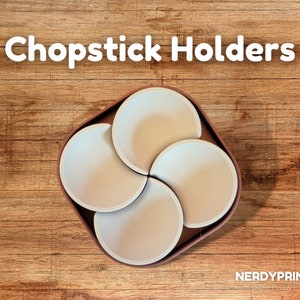 May include: A brown and white 3D printed chopstick holder with four individual slots. The holder is designed to hold chopsticks upright.
