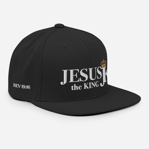 Könnte beinhalten: Schwarze Baseballkappe mit einer weißen gestickten Krone und dem Text "JESUS the KING" und "REV 19:16" auf der Vorderseite.