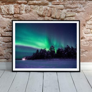 May include: A vibrant green aurora borealis, also known as the Northern Lights, illuminates the night sky above a snow-covered forest. The stars twinkle in the dark sky.