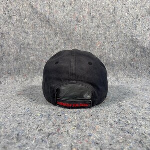 Puede incluir: Gorra de b&eacute;isbol negra con el texto "CHAMPIONSHIP UTAH RACING" en letras rojas. La gorra est&aacute; hecha de un material oscuro y texturizado y tiene una visera curva. La parte trasera de la gorra es visible, mostrando la correa ajustable.