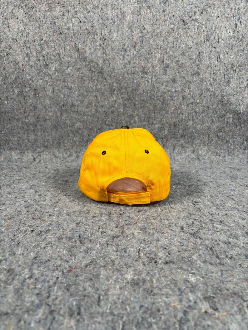 May include: A vibrant yellow baseball cap with a curved peak and a black adjustable strap. The cap features a classic six-panel design with black eyelets. The back of the cap is open for adjustment.