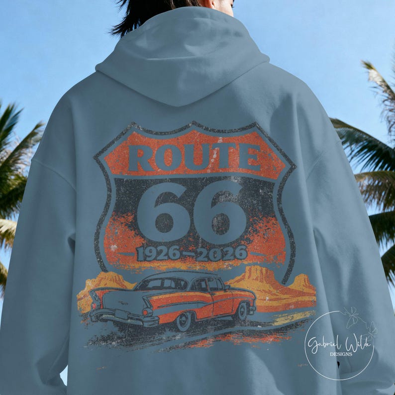 May include: A light blue hoodie featuring a distressed Route 66 design on the back. The design includes the words "ROUTE 66" above the number "66" and the years "1926-2026", along with an illustration of a classic car.