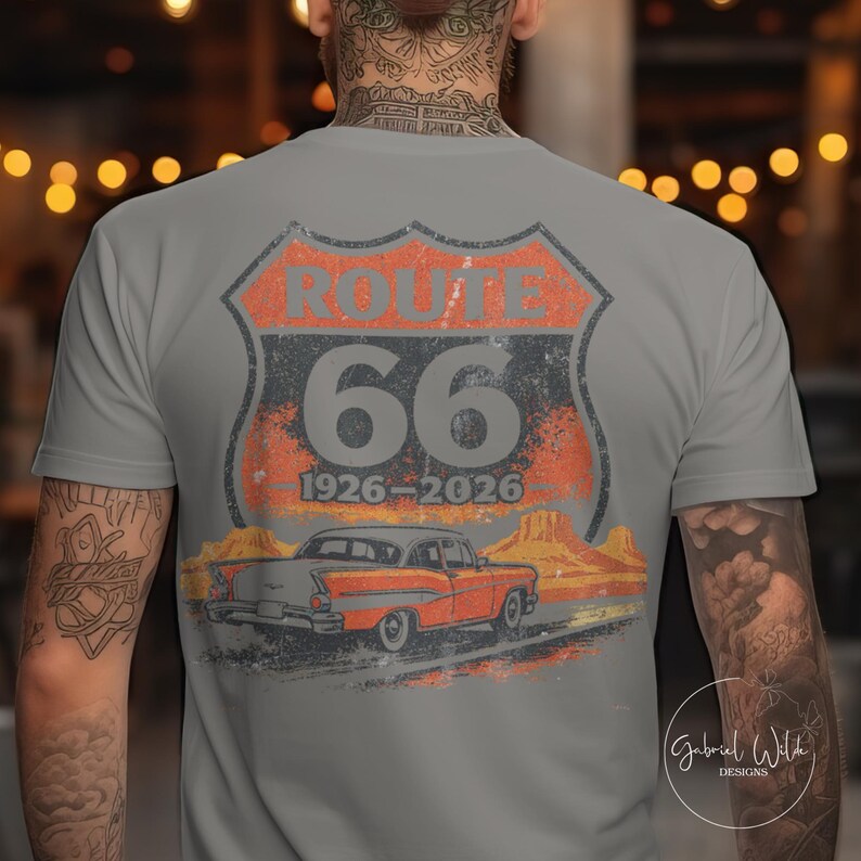 May include: Gray t-shirt featuring a distressed Route 66 design. The design includes the words "ROUTE 66" above the number "66", with the years "1926-2026" below. An orange classic car is depicted on a road with a desert landscape.