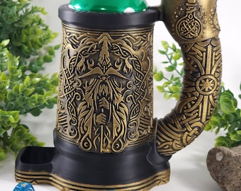 May include: A black and gold 3D printed can holder with a detailed design of a bearded man's face and intricate patterns. The holder has a built-in dice tray and a handle shaped like a dragon's head. Blue dice are scattered around the holder.
