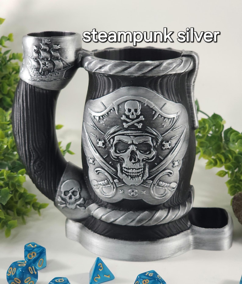 May include: Steampunk silver pirate skull dice tower with a wooden handle and a dice tray. The tower features a pirate skull with crossed swords and a skull and crossbones.