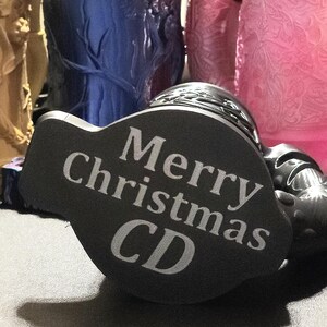 May include: Black and gray round bottle stopper with the text "Merry Christmas CD" engraved on the top.