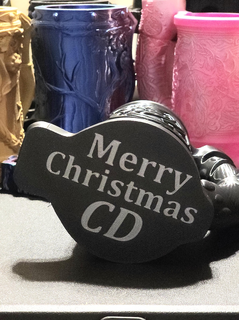 May include: Black and gray round bottle stopper with the text "Merry Christmas CD" engraved on the top.