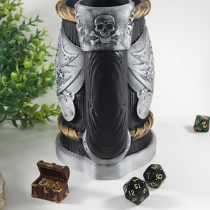 May include: A black and silver pirate-themed beer stein with a skull and crossbones design. The stein is surrounded by green dice and a small wooden treasure chest.