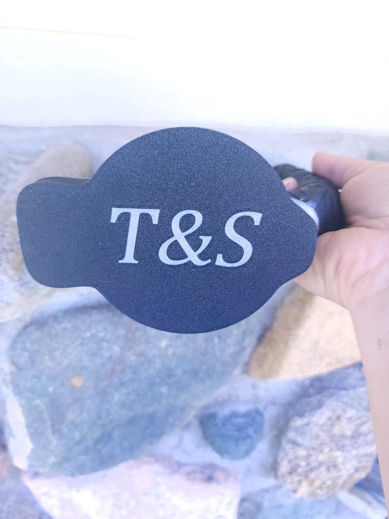 May include: Black round bottle stopper with a white inscription that reads "T&S".
