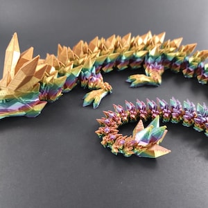 May include: A 3D printed iridescent dragon figurine with a long, segmented tail. The dragon is made of a rainbow of colors, including gold, purple, blue, and green.