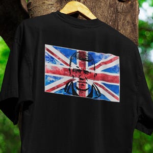 Op de afbeelding: Zwart T-shirt met een aquarelprint van een Union Jack-vlag met een mannengezicht in het midden.
