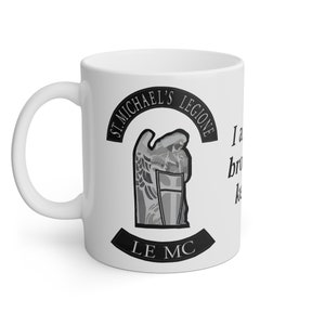 Op de afbeelding: Witte keramische mok met een zwart-grijze afbeelding van een engel met vleugels en een schild. De tekst "ST. MICHAEL'S LEGIONE LE MC" staat op de mok gedrukt.