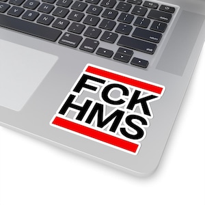 Peut inclure: Un autocollant blanc avec le texte "FCK HMS" en noir, souligné de blanc et accentué de barres horizontales rouges. L'autocollant est placé sur un ordinateur portable argenté.