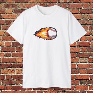 Puede incluir: Camiseta blanca con un diseño de béisbol en llamas. La pelota tiene costuras rojas y un contorno negro. Las llamas son naranjas y amarillas, creando una sensación de movimiento. La camiseta está hecha de tela blanca.