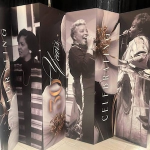 May include: A four-panel folding room divider featuring black and white photographic prints of individuals singing and speaking. The panels display the text "CELEBRATING" and "30 Years" alongside large, stylized floral graphics in shades of white and gold.