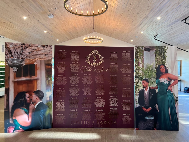 May include: A wedding seating chart with a burgundy background and gold lettering. The chart is divided into sections for each table, with the names of the guests listed under each table number. The chart also includes the names of the bride and groom, "Justin + Saketa", and the date of the wedding, "10.21.22".