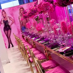 K&ouml;nnte beinhalten: Ein langer Tisch mit einer rosa Tischdecke und goldenen St&uuml;hlen ist f&uuml;r eine Party gedeckt. Der Tisch ist mit rosa Blumen und durchsichtigen Glasvasen dekoriert. Auf dem Tisch liegen rosa Servietten und durchsichtige Gl&auml;ser.