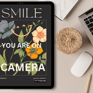 以下が含まれることがあります： 黒いタブレットに、花柄のデザインと「SMILE YOU ARE ON CAMERA #00457 pencil edition SAFETY AND SECURITY SOURCE」というテキストが画面に表示されています。