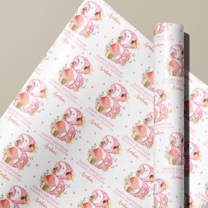 Peut inclure: Papier d'emballage rose avec un motif r&eacute;p&eacute;t&eacute; d'une f&eacute;e avec une robe et des ailes roses, assise sur un champignon avec une petite maison. Le texte "Happy Birthday to a special daughter Ambar" est r&eacute;p&eacute;t&eacute; sur tout le papier.