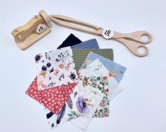 May include: A set of fabric squares in various patterns and colors, including floral, geometric, and solid colors. The fabric squares are arranged in a pile, with a wooden sewing machine and a pair of wooden tongs in the background.
