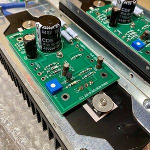 May include: Close-up of a green circuit board with electronic components, including capacitors, resistors, and a transistor. The board is labeled with the text "(C) 2018 NELSON PASS".