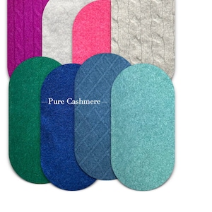 May include: A collection of oval-shaped fabric swatches in various colours and textures, including pink, green, blue, and grey. The swatches are arranged in a semi-circle and labelled "Pure Cashmere".