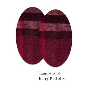 Può includere: Due toppe in tessuto di forma ovale con un motivo a quadri in tonalità rosso intenso, bordeaux e marrone scuro. La consistenza appare morbida e soffice, tipica della lana. Sotto le toppe, il testo recita Lambswool — Berry Red Mix —.