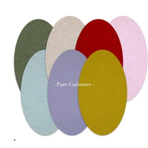 Può includere: Una collezione di sei campioni di tessuto ovali in diversi colori, tra cui verde, beige, rosso, azzurro, viola e giallo. I campioni sono disposti a semicerchio e il testo "Pure Cashmere" è stampato al centro.
