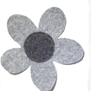Op de afbeelding: Een vijfbladige bloemapplicatie gemaakt van lichtgrijze gemêleerde stof. Het midden van de bloem is voorzien van een cirkelvormige donker antracietgrijze patch met zichtbare stiksels langs de rand, wat een eenvoudig en plat decoratief textielelement vormt.