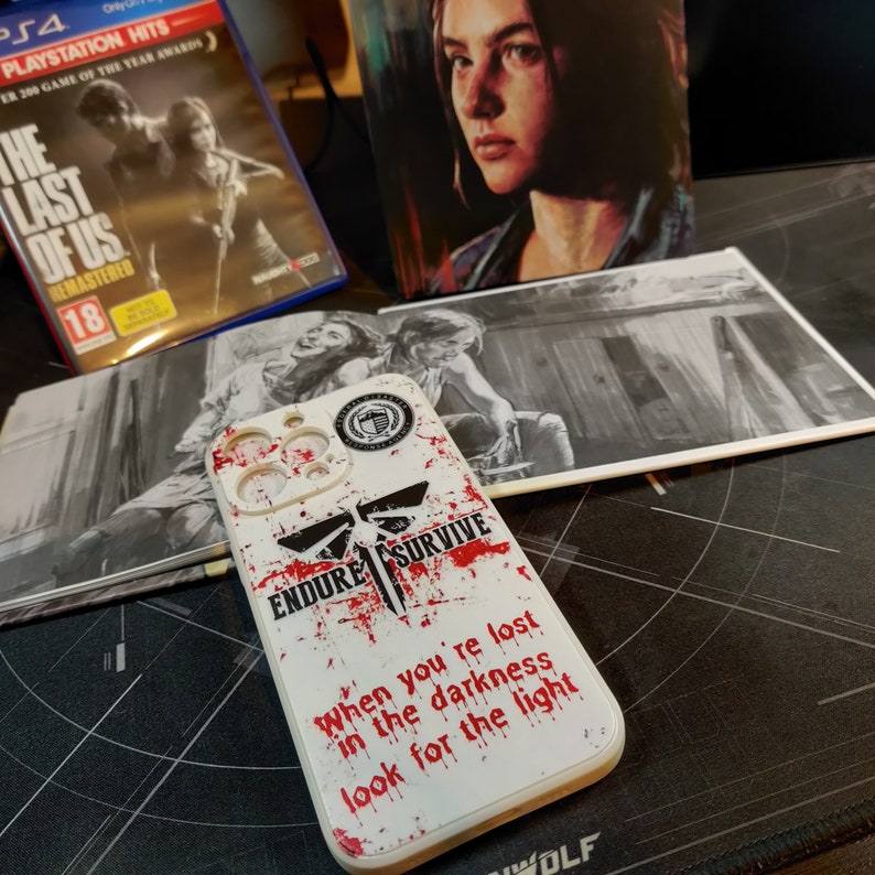 May include: White phone case with a red and black graphic design. The design features a stylised dragonfly with the words "Endure Survive" and the text "When you're lost in the darkness look for the light".