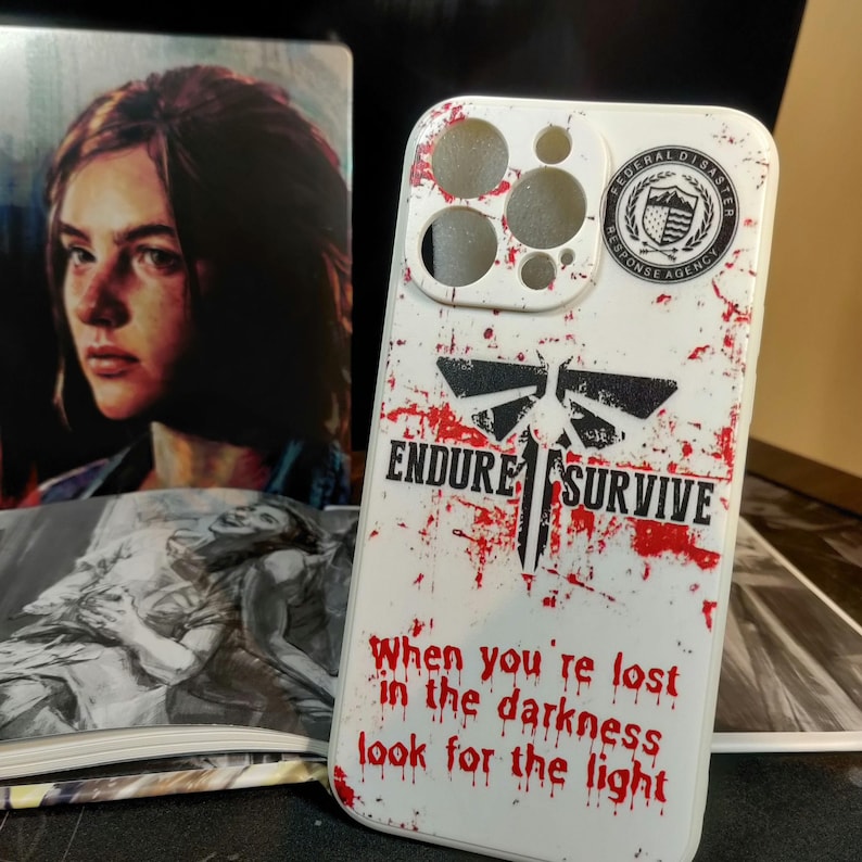 May include: White phone case with a red and black graphic of a firefly with the words "Endure Survive" and "When you're lost in the darkness look for the light". The case also has a sticker of the Federal Disaster Response Agency logo.