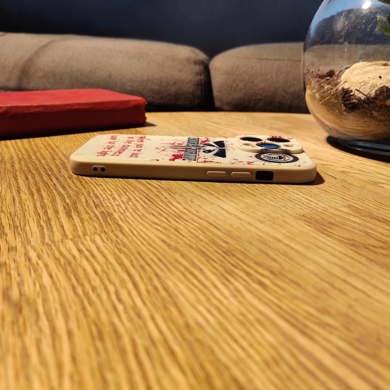 May include: A white phone case with a red and black graphic design. The design features a skull and crossbones with the text "May the odds be ever in your favour".