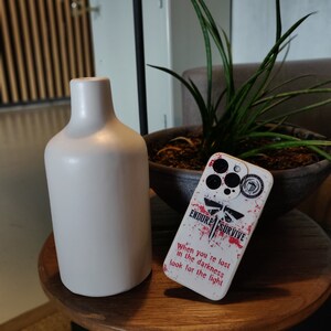 May include: White phone case with a red and black graphic design. The design features a firefly, the words "Endure" and "Survive", and the text "When you're lost in the darkness look for the light".
