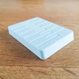 May include: A light blue rectangular soap dish with raised ridges on the top surface.
