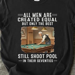 Peut inclure: T-shirt noir avec un motif représentant une scène de billard et le texte "ALL MEN ARE CREATED EQUAL BUT ONLY THE BEST STILL SHOOT POOL - IN THEIR SEVENTIES." Le mot "Black" est imprimé en bas.
