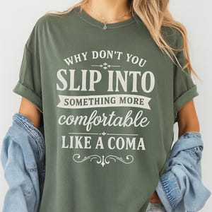Peut inclure: T-shirt vert mousse avec l'inscription blanche : « WHY DON'T YOU SLIP INTO SOMETHING MORE comfortable LIKE A COMA ». Le t-shirt a des manches retroussées et est porté avec une veste en jean et un short.