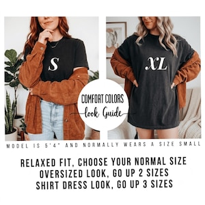 May include: A Comfort Colors look guide featuring two side-by-side images of a black t-shirt in size S and XL. Text includes: Comfort Colors look guide, Model is 5'4" and normally wears a size small, Relaxed fit, choose your normal size, Oversized look, go up 2 sizes, Shirt dress look, go up 3 sizes.