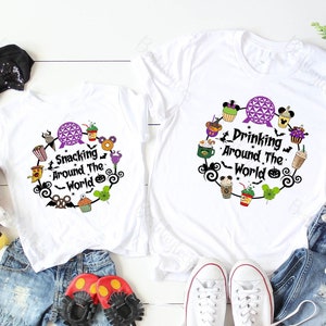 May include: Two white t-shirts with the phrases "Snacking Around The World" and "Drinking Around The World" in black script. Each shirt features a circular design with food and drink illustrations, including a purple sphere and Mickey Mouse icons.