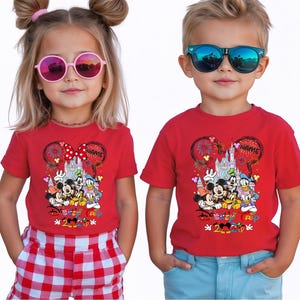 May include: Two children wearing red t-shirts with a Disney graphic. The shirts feature Mickey Mouse, Minnie Mouse, Donald Duck, and Goofy in front of a castle, with the text "Disney 2020 RIP". The girl wears pink sunglasses and the boy wears blue sunglasses.