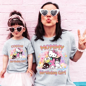 May include: Two light gray t-shirts with a colorful graphic of cartoon characters and the text "MOMMY OF THE BIRTHDAY GIRL" and "COUSIN OF THE BIRTHDAY GIRL". The shirts are worn by two people, one wearing heart-shaped sunglasses.