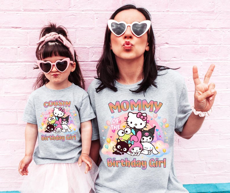 May include: Two light gray t-shirts with a colorful graphic of cartoon characters and the text "MOMMY OF THE BIRTHDAY GIRL" and "COUSIN OF THE BIRTHDAY GIRL". The shirts are worn by two people, one wearing heart-shaped sunglasses.