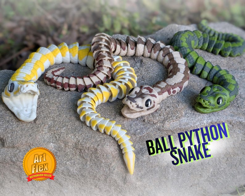 Pode incluir: Tr&ecirc;s brinquedos articulados de cobra p&iacute;ton bola em amarelo, castanho e verde, sobre uma superf&iacute;cie de pedra. A cobra amarela tem detalhes em branco, a cobra castanha tem detalhes em bege e branco, e a cobra verde tem detalhes em verde escuro. O texto "BALL PYTHON SNAKE" &eacute; vis&iacute;vel.