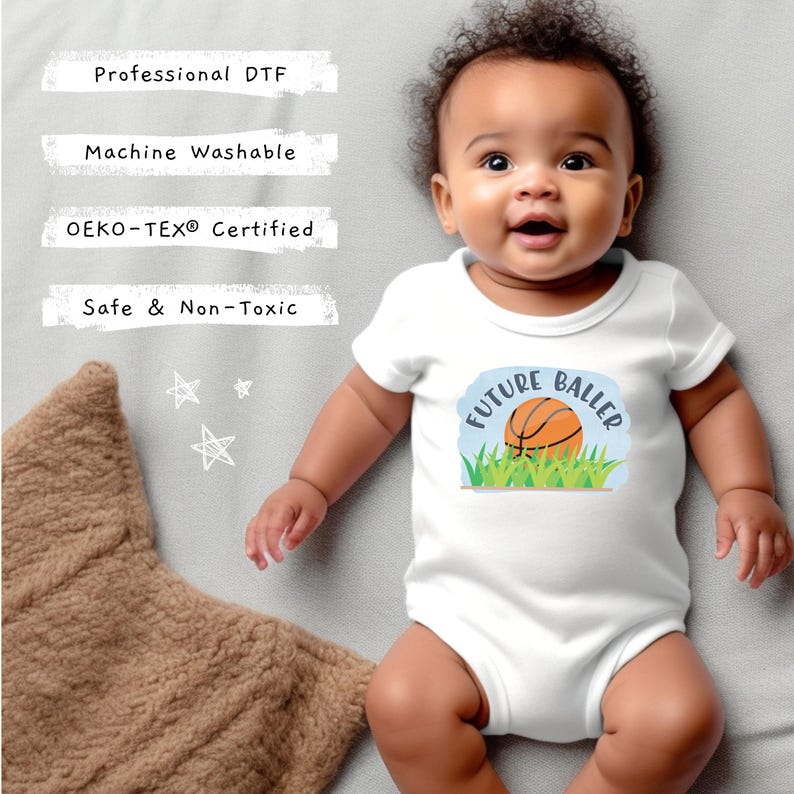 May include: A white baby bodysuit featuring a graphic of a basketball in green grass with the text "FUTURE BALLER". The image includes text labels: Professional DTF, Machine Washable, OEKO-TEX Certified, and Safe & Non-Toxic.