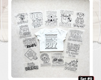 May include: A white short-sleeve baby bodysuit featuring the text "HANDSOME little GUY" surrounded by a checkered border, displayed with twelve iron-on transfers featuring various black and white graphic designs and phrases like "SLOTH MODE".