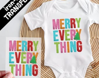 May include: A white short-sleeved baby bodysuit featuring a multi-coloured glittery graphic that reads MERRY EVERYTHING with a small green Christmas tree replacing the letter I. A separate matching iron-on transfer sheet is also visible.